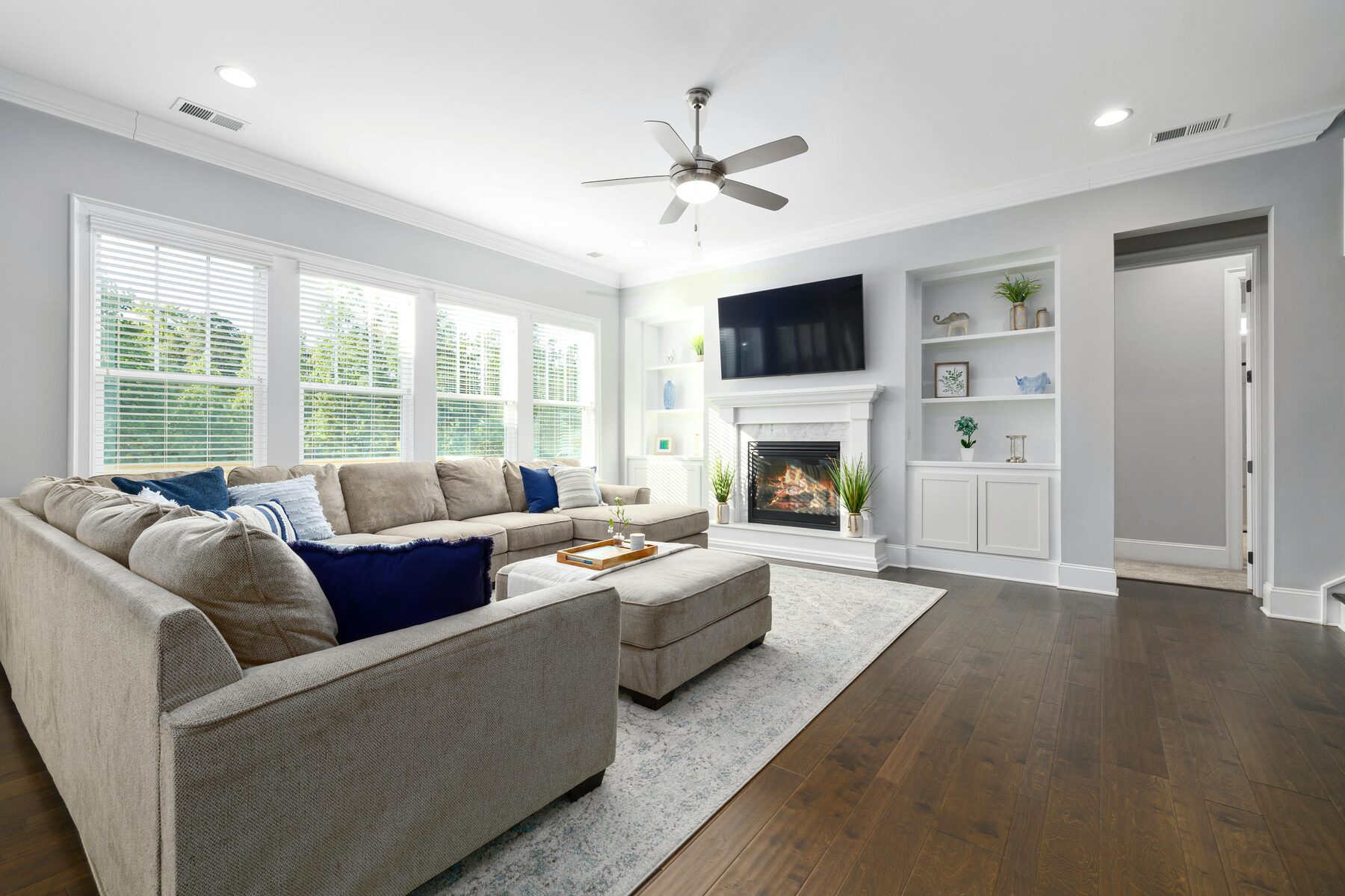 Living room with fireplace, mounted television, built-in shelves and gray sectional sofa