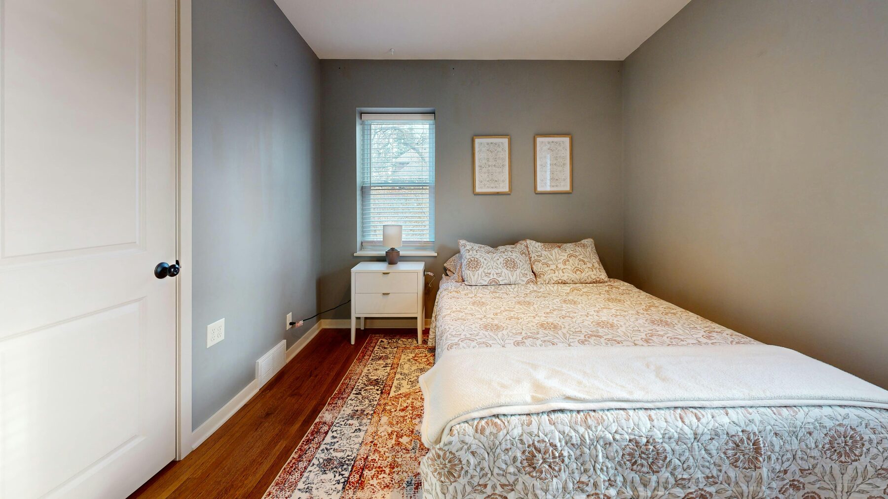 Private bedroom with floral bedding and hardwood floors